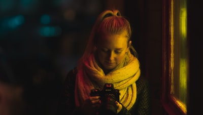 弱光摄影的女人在围巾使用相机
